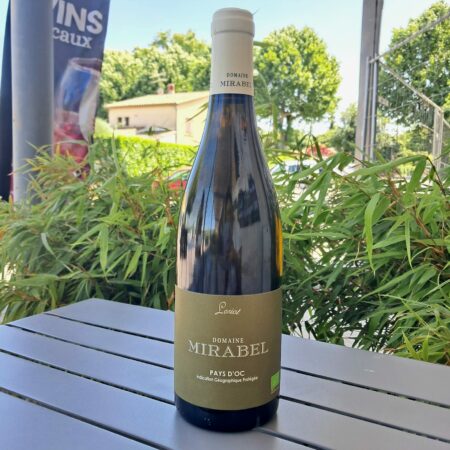 Bouteille de vin blanc Le Loriot Mirabel posée sur une table en bois avec fond de vignes